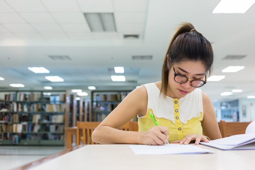 girl writing in libary